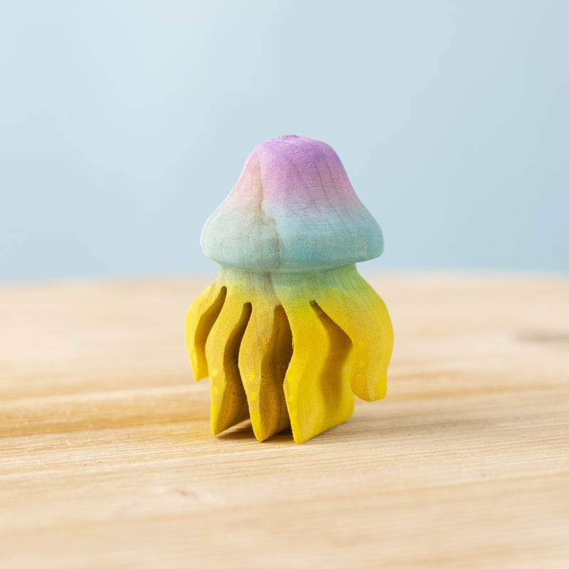 Colorful jellyfish-shaped object on a wooden surface with a light blue background