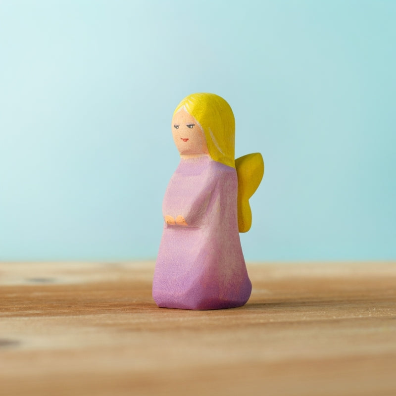 Small figurine of a person with blonde hair and a purple outfit on a wooden surface with a light blue background