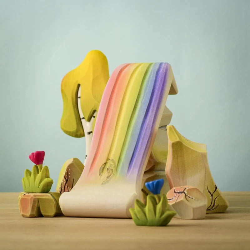 Colorful rainbow-shaped object on a wooden surface with a light blue background