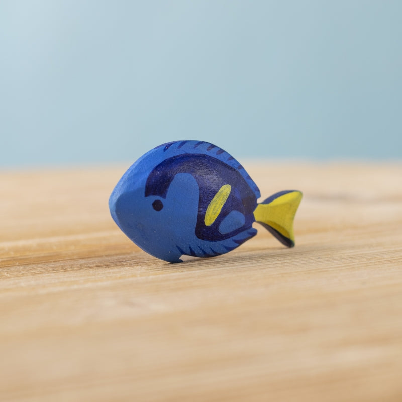Blue fish-shaped object on a wooden surface with a light blue background