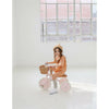 A child riding a pink Banwood toddler trike indoors with a big window in the background.